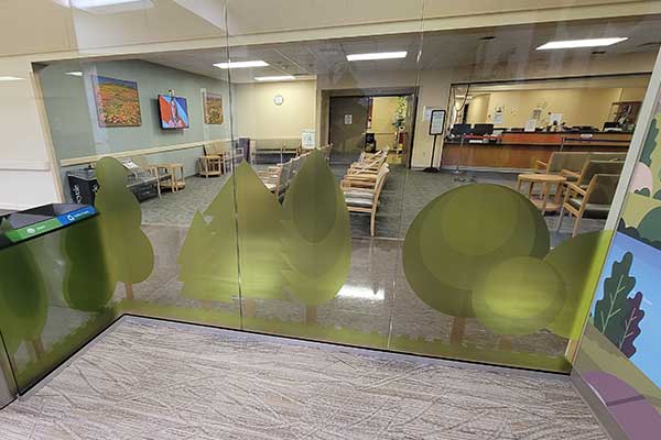 Optically clear printed green tree graphics applied to a reception area glass wall