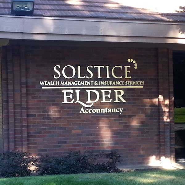 Dimensional metal letters reading Solstice Wealth Management and Elder Accountancy installed on a brick building facade